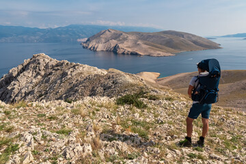 Father with baby carrier on hiking trail with panoramic aerial view of Otok Prvic near coastal town...