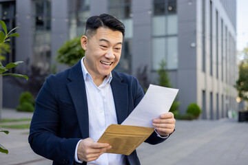 Joyful businessman celebrating good news with a letter outdoors