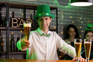 Young bartender with beer in pub on St. Patrick's Day