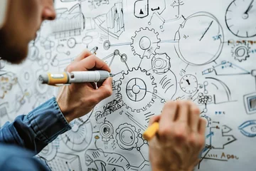 Fotobehang A person sketching interconnected gears on a whiteboard, symbolizing the breakdown and analysis of complex mechanical concepts. © Degimages