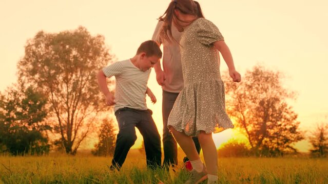 Family team, sports games. Children son daughter play football with father on lawn. Boy girl parent run after red ball in park. Active happy family, child dad having fun playing ball on green grass.