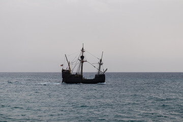 Silhouette of sailing boat ship on the majestic Atlantic Ocean seen from beach Praia Santa Cruz,...