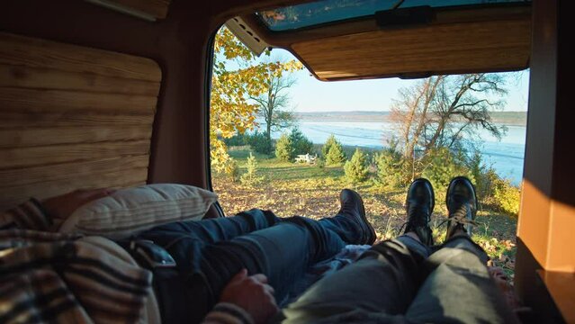 Family resting inside a camper van, captures the essence of autumn with a view of a tranquil lake and golden foliage.
