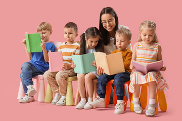 Little children with nursery teacher reading books on pink background
