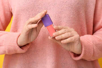 Woman holding liquid pink lipstick, closeup