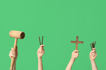 Female hands with wooden mallet, cross and nails on green background. Good Friday concept
