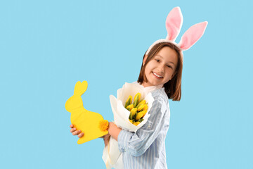 Cute little girl with Easter bunny ears, flowers and decorative rabbit on blue background