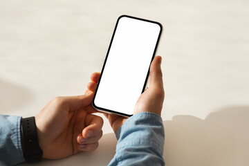 Hands of a person holding a smartphone with a blank screen, wearing a blue denim shirt