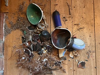 Close up of broken ceramic art and antique china vase, vintage bowl contain lavender and plates shapes and colour pieces destroyed by fall from collapsed mantelpiece to oak wood floor in old house