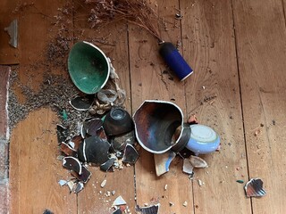 Close up of broken ceramic art and antique china vase, vintage bowl contain lavender and plates shapes and colour pieces destroyed by fall from collapsed mantelpiece to oak wood floor in old house