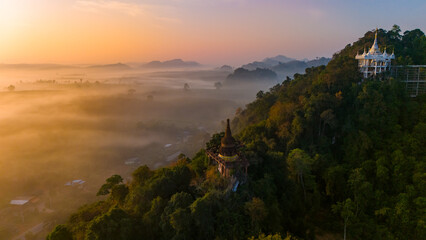 Beautiful sunrise with Buddhist temples on the top of cliff, morning mist at Khao Na Nai Luang...