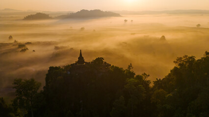 Beautiful sunrise with pagodas on the top of cliff, morning mist at Khao Na Nai Luang Dharma Park, Surat Thani province, Thailand