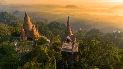 Beautiful sunrise with pagodas on the top of cliff, morning mist at Khao Na Nai Luang Dharma Park, Surat Thani province, Thailand
