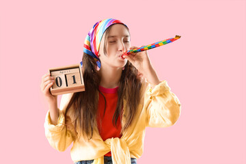 Funny little girl with party blower and calendar on pink background. April Fools' Day celebration