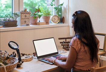 Woman works on laptop with blank screen on office desk near window. Workplace during home office. Cozy place to study.