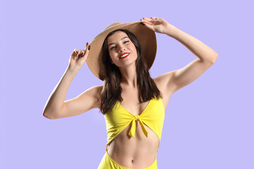 Beautiful young woman in beachwear on lilac background