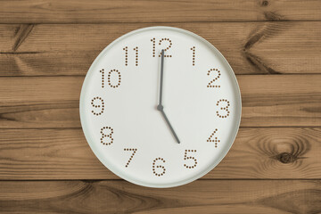 Round white wall clock at 5 o'clock on brown wood background. concept of daily regime, wake up...