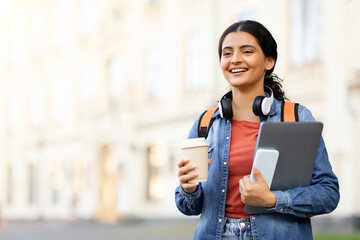 Positive eastern woman student with takeaway coffee and smartphone