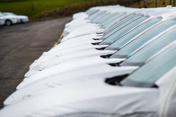 Long row of cars ready to be delivered at a car dealership.