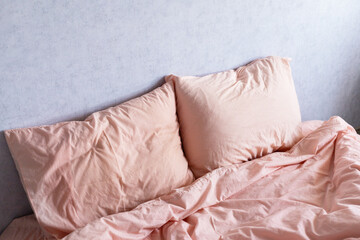 bed linen peach fuzz color on the background of a gray wall