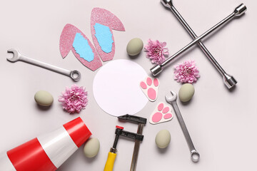 Composition with blank card, tools for car repair and Easter eggs on light background