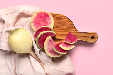 Wooden board with pieces of ripe watermelon radish on pink background