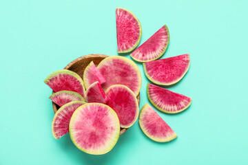 Wooden bowl with cut ripe watermelon radish on blue background
