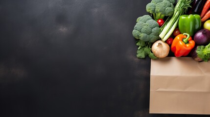 Some fresh vegetables and fruit in a paper bag on a dark background. Raw food concept for daily...