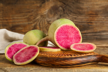 Board with ripe watermelon radishes on wooden background
