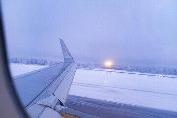 Fototapeta premium Snow storm foggy landscape airplane window scene while taking off in an airport covered in frozen winter snow in Rovaniemi, Finland