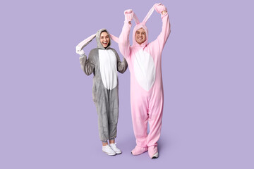 Beautiful young couple in bunny costume on purple background. Easter celebration