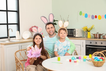 Father with children sitting at table in kitchen decorated for Easter celebration