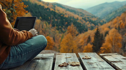 Man using the laptop or notebook device outdoors in the wilderness, autumn or fall forest landscape, remote work or freelancing on a holiday or a vacation. Digital nomad traveling freedom, copy space