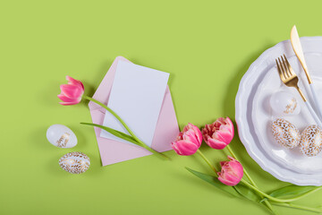 Pink tulips and table place setting with empty greeting or invitation card
