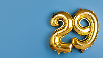 Banner with number 29 golden balloon with copy space. twenty nine years anniversary celebration concept on a blue background.