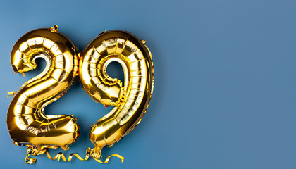 Banner with number 29 golden balloon with copy space. twenty nine years anniversary celebration concept on a blue background.