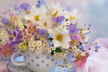 Bouquet of spring and summer flowers in a cup on the table, aquilegia, spirea, anemone, forget me not flowers, pansies, violet, beautiful postcard, closeup, blur. - 756792230