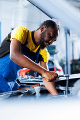 Engineer expertly examines car radiator using advanced mechanical tools, ensuring optimal automotive performance and safety. BIPOC licensed garage employee conducts annual vehicle checkup