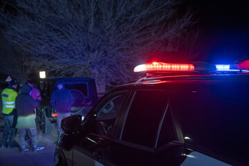 police officer stands next to a car he pulled over for speeding, reaching for the driver's ID,...