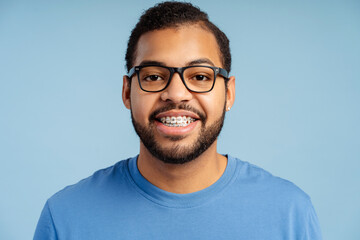 Smiling African American male student with braces in a casual t-shirt and glasses, looking at camera