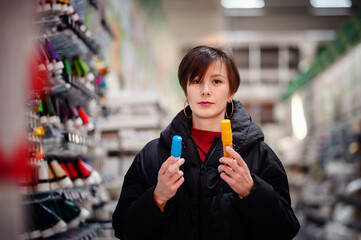 With a joyful expression, an artist holds up tubes of paint, contemplating her next vibrant creation, while her casual attire and headphones blend into the creative shopping experience