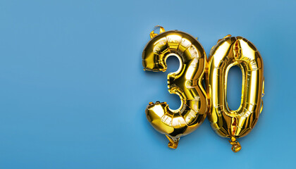 Banner with number 30 golden balloon with copy space. thirty years anniversary celebration concept on a blue background.