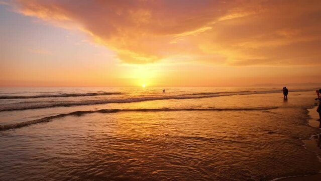 Atlantic ocean sunset with surging waves with people silhouettes at Fonte da Telha beach, Costa da Caparica, Portugal