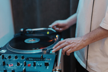 Close-up of a DJ's hands adjusting controls on a turntable, concept of live music and entertainment.