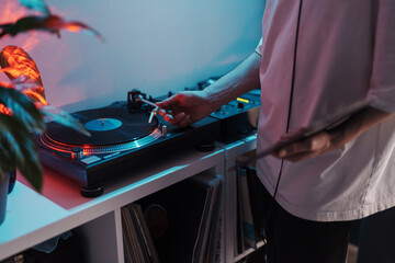 Close-up of a DJ's hands mixing tracks on a vinyl turntable with LED lights.