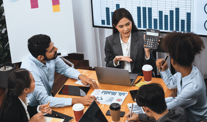 Top view multiracial analyst team use BI dashboard data to analyze financial report on meeting table. Group of diverse business people utilize data analysis by FIntech for business decision. Concord