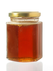 Glass bottle of fine honey with golden lid on white background. Agriculture organic product famous for its sweet taste and health benefits and value.