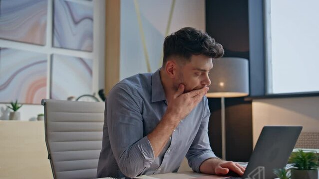 Tensed boss typing laptop keyboard at private cabinet closeup. Man touching head