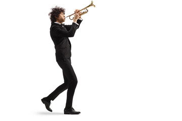 Male musician in a black suit walking and playing a trumpet