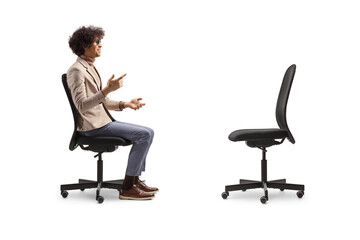 Profile shot of a man talking and sitting in an office chair opposite an empty chair